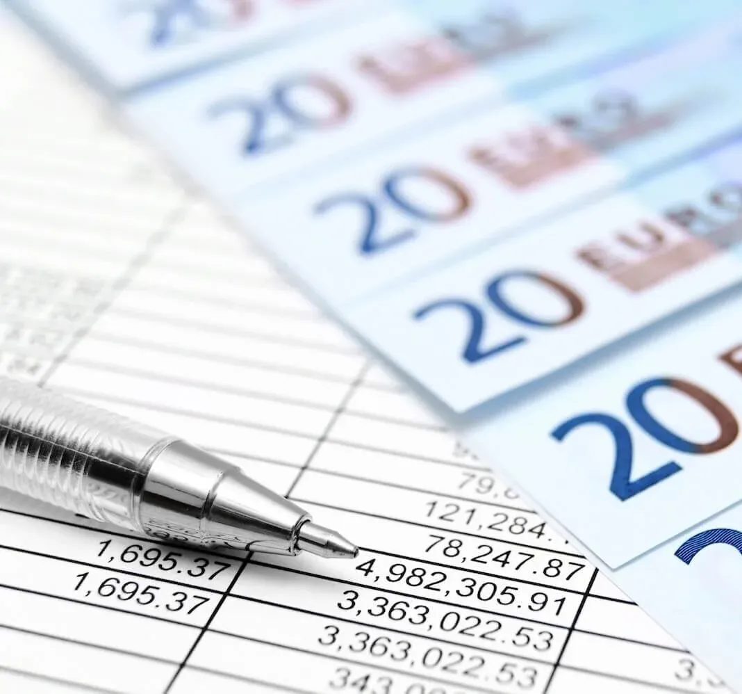 Lohn und Gehaltsabrechnung mit Euro Scheinen und Tabelle im Hintergrund