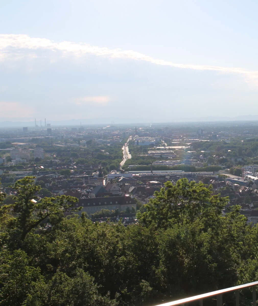 Zwei Personen stehen an einem Geländer und blicken von einem Aussichtspunkt über die Stadt und grüne Landschaft. - karlsruhe